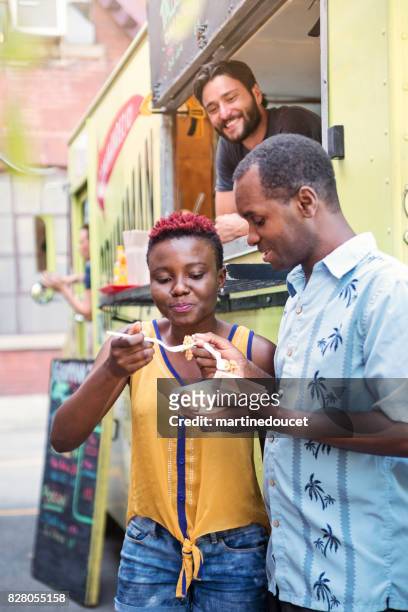 African-american couple enjoying their lunch from food truck in city street.