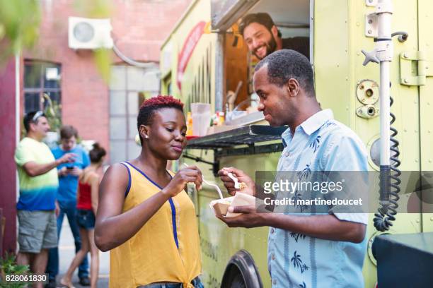 couple afro-américain appréciant leur déjeuner de camion de nourriture dans la rue de la ville. - montreal black and white photos et images de collection