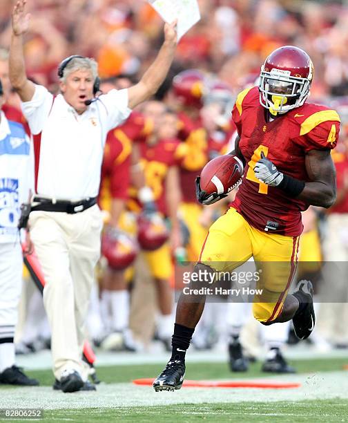 Joe McKnight of the USC Trojans rushes the ball 24-yards as head coach Pete Carroll reacts in the second quarter while taking on the Ohio State...