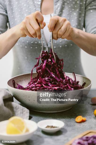 a woman is photographed as she is mixing a red cabbage salad - cabbage stock pictures, royalty-free photos & images