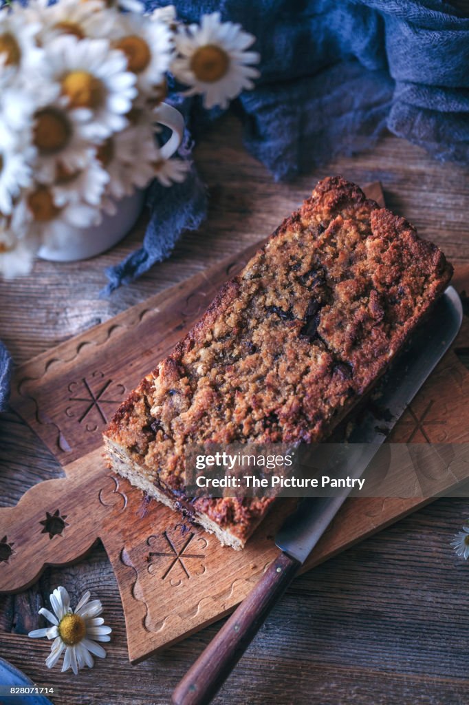 Loaf of baked chocolate chip banana bread on a wooden serving board