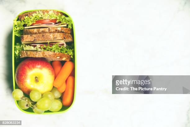 green school lunch box with sandwich, apple, grape and carrot close up on white background. healthy eating habits concept. - packed lunch - fotografias e filmes do acervo