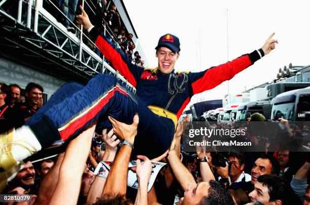 Sebastian Vettel of Germany and Scuderia Toro Rosso is thrown high in the air by team mates in the paddock after winning the Italian Formula One...