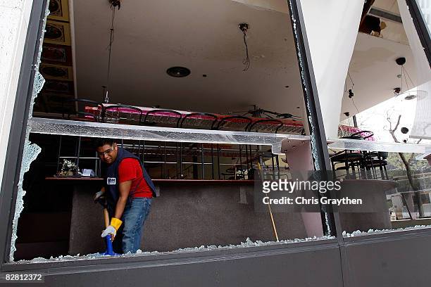 Worker cleans up glass blown in by high winds from Hurricane Ike September 14, 2008 in Houston, Texas. Ike caused extensive damage along the Texas...