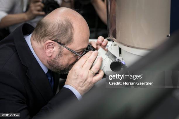 Candidate for the german chancellorship of the Social Democratic Party of Germany , Martin Schulz, looks through a microscope in a laboratory during...