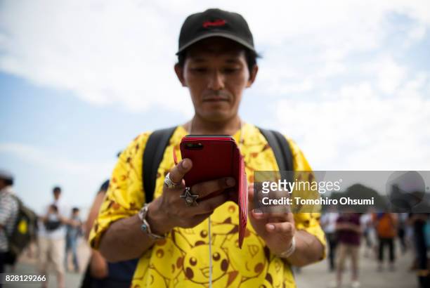 Man plays Nintendo Co.'s Pokemon Go augmented reality game on his smartphone during the Pikachu Outbreak event hosted by The Pokemon Co. On August 9,...