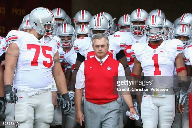 Head coach Jim Tressel of the Ohio State Buckeyes leads teammates Alex Boone and Marcus Freeman out onto the field before the college football game...