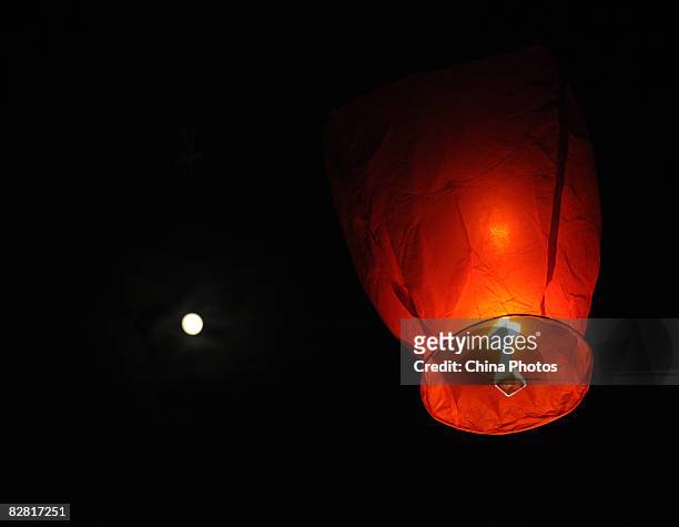 The moon shines above as residents fly the Kongming Sky Lantern to mark the Mid-Autumn Moon Festival on September 14, 2008 in Chengdu, Sichuan...