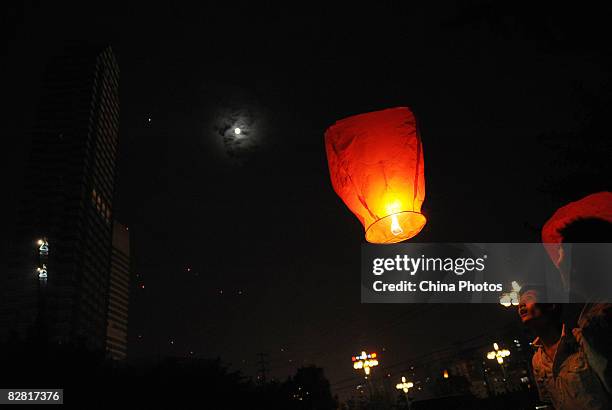 The moon shines above as residents fly the Kongming Sky Lantern to mark the Mid-Autumn Moon Festival on September 14, 2008 in Chengdu, Sichuan...