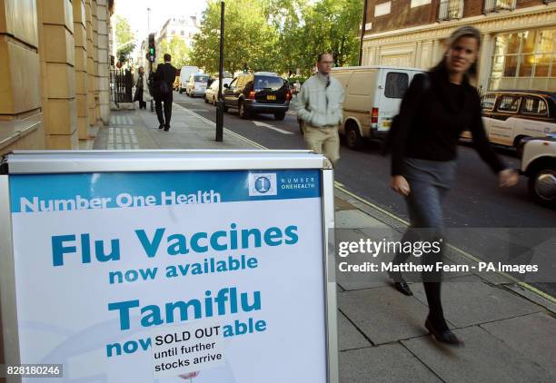 Pedestrians walk past a sign outside a private clinic in London's Harley Street district which states that stocks of the bird flu vaccine Tamiflu...