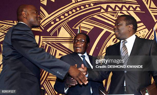 Zimbabwean MDC breakaway faction leader Arthur Mutambara shakes hands with opposition's leader Morgan Tsvangirai under the look of Zimbabwe's...