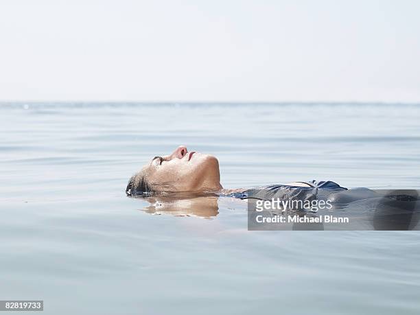 woman floats in the water - drijven stockfoto's en -beelden