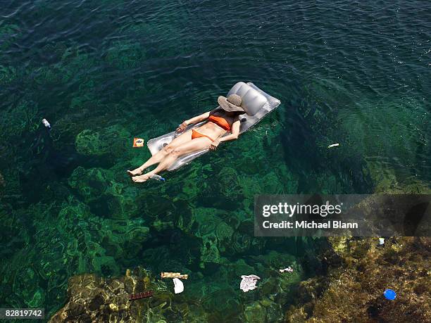 woman floats in the sea amongst trash - pool raft stock pictures, royalty-free photos & images