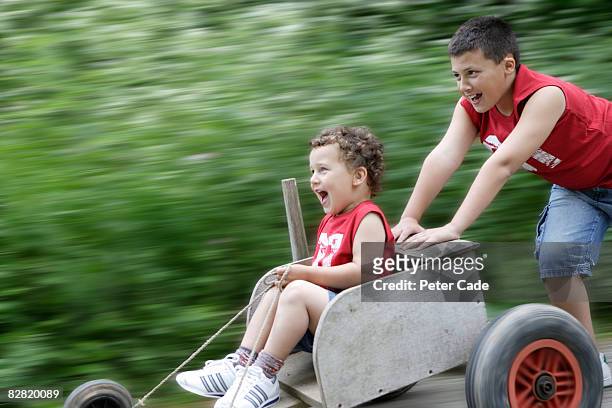 boy being pushed in go kart by brother - soapbox cart stock pictures, royalty-free photos & images