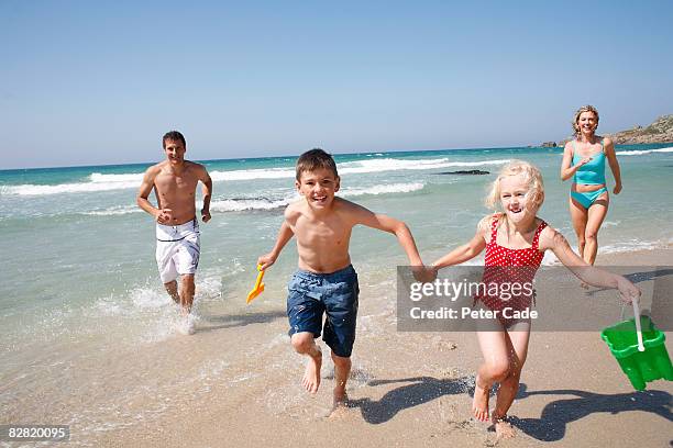 family running on beach - boy and girl running along beach holding hands stock-fotos und bilder