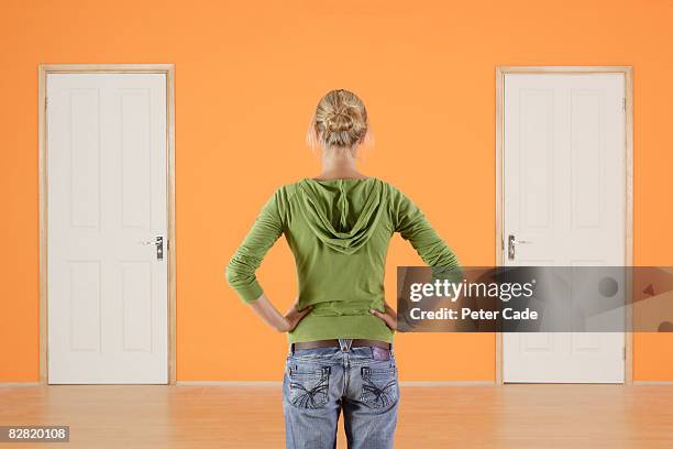 woman stood with hands on hips looking at two door - certain stock pictures, royalty-free photos & images