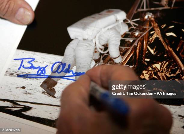 Astronaut Buzz Aldrin signing a photo at the International Autograph Auction show held near Heathrow, Saturday October 29, 2005. Other items on sale...