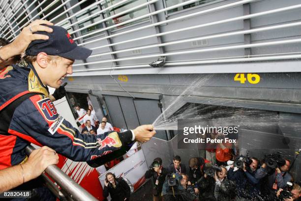 Sebastian Vettel of Germany and Scuderia Toro Rosso sprays champage as he celebrates with team mates in the paddock after winning the Italian Formula...