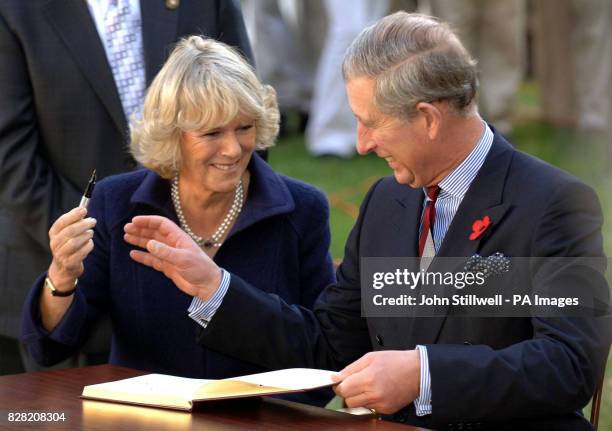 The Prince of Wales and the Duchess of Cornwall giggle as they sign the visitors book at the Seed School on the outskirts of Washington DC Wednesday...