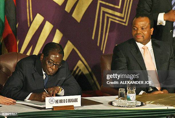 Zimbabwe President Robert Mugabe signs the power-sharing accord under the look of King Mswati III of Swaziland on September 15, 2008 in Harare....