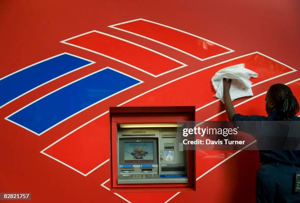 Queen Elizabeth Johnson, an employee of Redlee/SCS Group, cleans the front of an atm machine across the street from Bank of America's headquarters on...