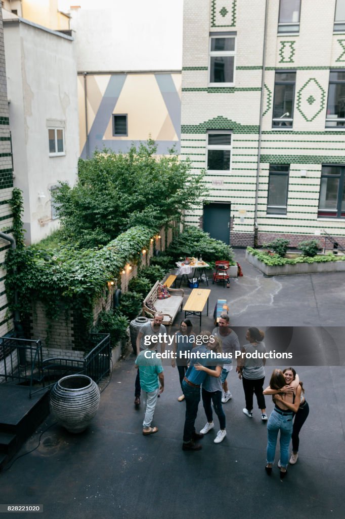 Group Of Friends Meeting Up In Courtyard For A Barbecue