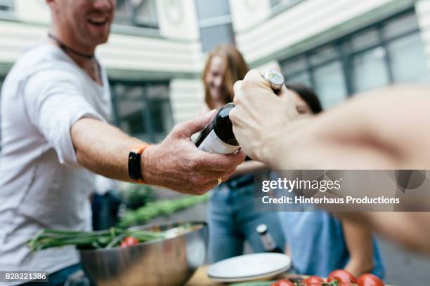 man handing a beer to his friend - anbieten stock-fotos und bilder