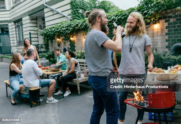 two young men and their friends catching up over a barbecue - german greens party stockfoto's en -beelden