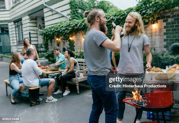 two young men and their friends catching up over a barbecue - german greens party stock pictures, royalty-free photos & images