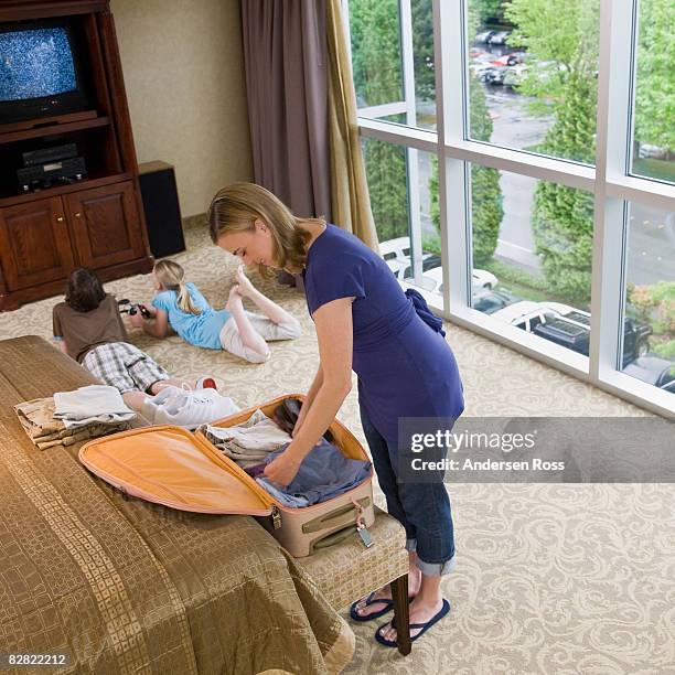 mother packing a suit case while kids play games - teen packing suitcase stock pictures, royalty-free photos & images