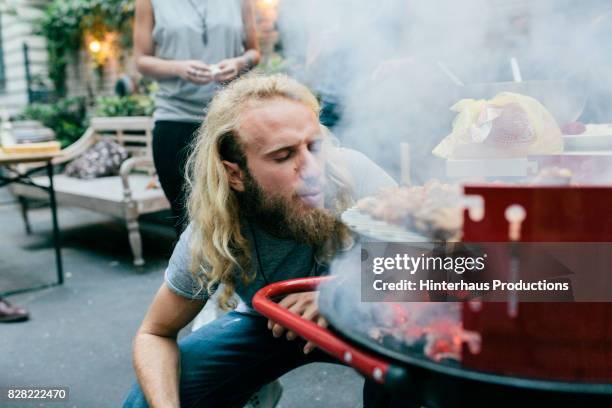 young man heating up barbecue at party - barbeque stock pictures, royalty-free photos & images