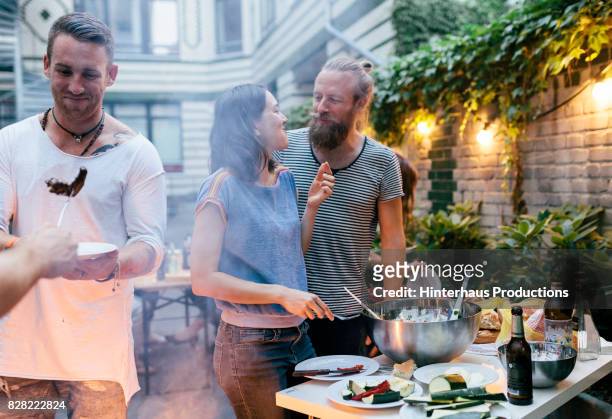couple having barbecue with friends looking at each other fondly - barbecue social gathering stock pictures, royalty-free photos & images