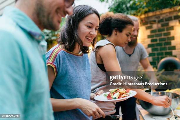 friends having summer barbecue together line up for food - barbecue stock-fotos und bilder