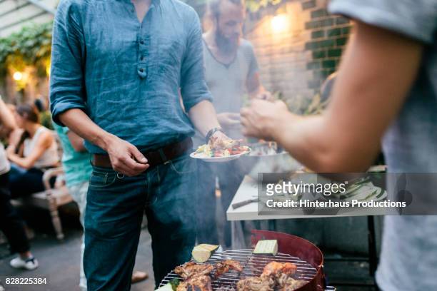 group of friends serving food straight from barbecue at evening get together - friends smoking stock pictures, royalty-free photos & images