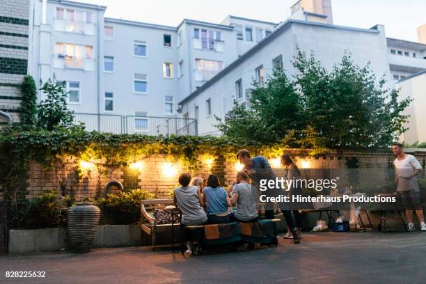 group of friends enjoying evening barbecue meal together - urban lifestyle fotografías e imágenes de stock