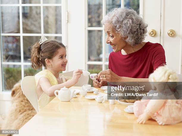 hispanic grandmother having tea party with granddaughter - tea party stock pictures, royalty-free photos & images