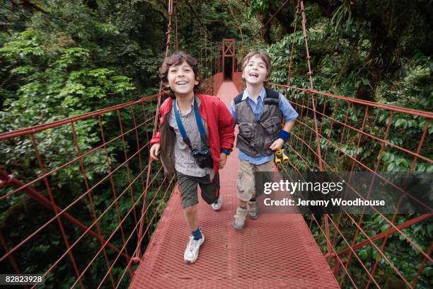 hispanic boys on suspension bridge in woods - hängbro bildbanksfoton och bilder