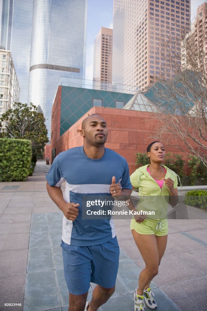 African couple jogging on city sidewalk