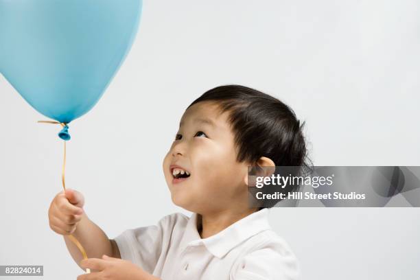 korean boy looking at balloon - child balloon studio photos et images de collection