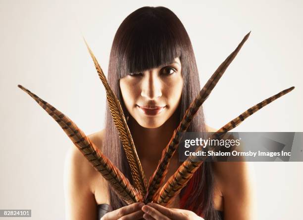 hispanic woman holding feathers - asymmetry stock pictures, royalty-free photos & images