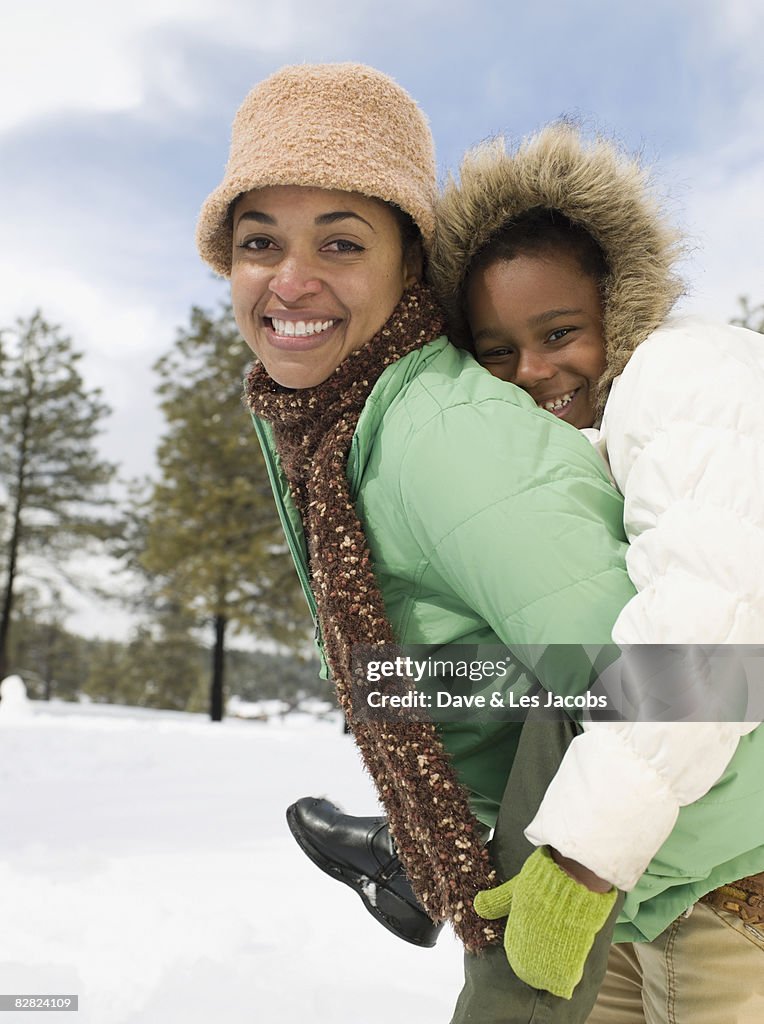 African mother giving daughter piggyback ride