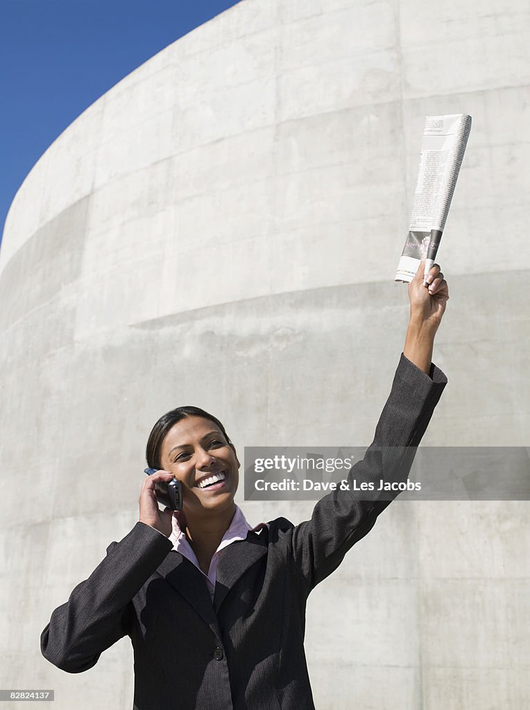 Indian businesswoman talking on cell phone with newspaper