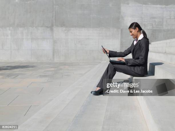 indian businesswoman working on laptop outdoors - profile laptop sitting stock-fotos und bilder