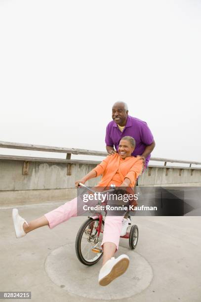 senior african couple playing on tricycle - couple de vieux drole photos et images de collection