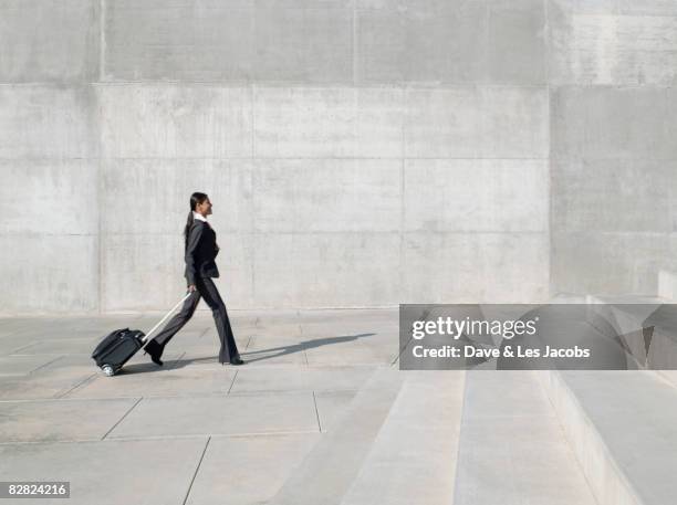 indian businesswoman pulling rolling luggage - luggage trolley stock-fotos und bilder