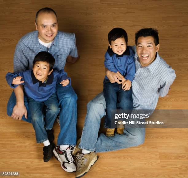 asian fathers holding sons in lap - uncle nephew stock pictures, royalty-free photos & images