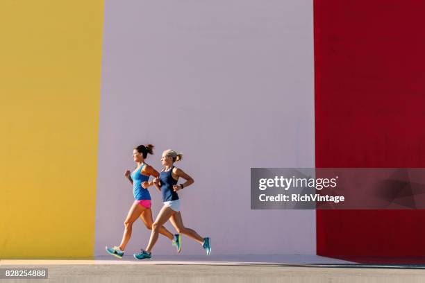 mulheres correndo na cidade contra a parede de cor - corrida fora de pista - fotografias e filmes do acervo