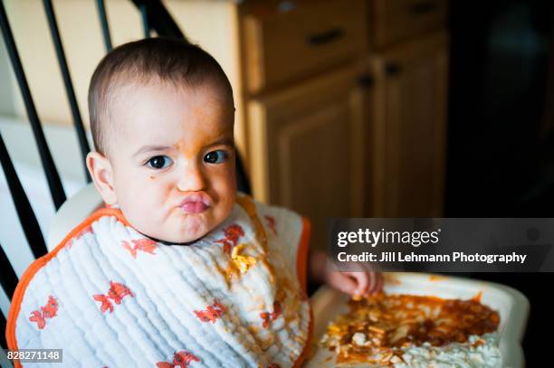12 month fraternal twin baby boy puckers while having food all over his face - よだれ掛け ストックフォトと画像