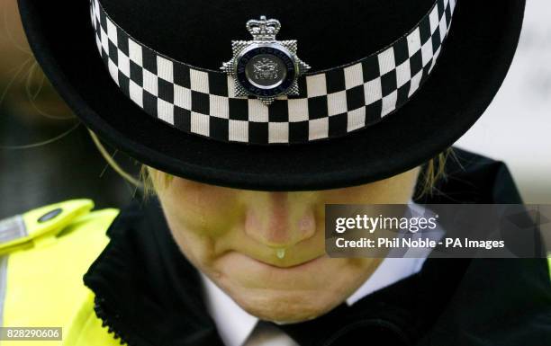 An unidentified police officer cries as she waits the passing of a horse-drawn carriage carrying the coffin of murdered police officer Sharon...