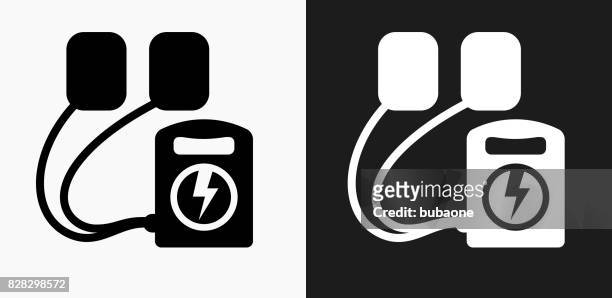 defibrillator icon on black and white vector backgrounds - defibrillation stock illustrations
